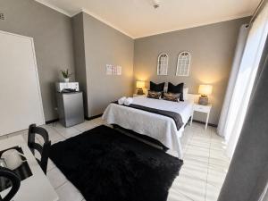 a bedroom with a large bed and a black rug at Zhantique Guest House 2- Unit 4 in Boksburg