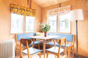 a dining room with a table and chairs and a vase of flowers at Bacton Beach Cabin in Bacton