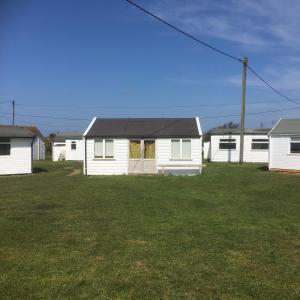 a row of white houses in a yard at Bacton Beach Cabin in Bacton