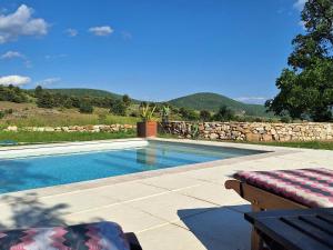 a swimming pool with a bench next to a stone wall at le clos d'Yrem in La Rochegiron
