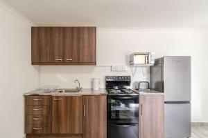 a kitchen with wooden cabinets and a stainless steel refrigerator at Sintha guest house in Kraaifontein