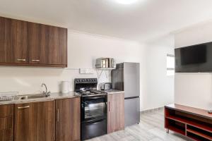 a kitchen with stainless steel appliances and wooden cabinets at Sintha guest house in Kraaifontein +11 photos