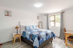 a bedroom with a bed with a blue and white comforter at Sintha guest house in Kraaifontein