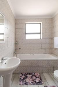 a white bathroom with a tub and a sink at Sintha guest house in Kraaifontein