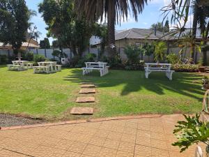 three picnic tables on the grass in a yard at Zhantique Guest House 2- Unit 4 in Boksburg +4 photos