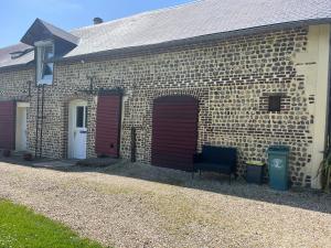 a brick building with two garage doors and a chair at Le champ de l alouette in Bec-de-Mortagne
