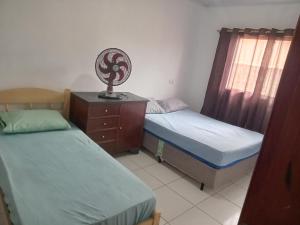 a bedroom with two beds and a dresser with a fan at Ambiente familiar em Poços de caldas in Poços de Caldas