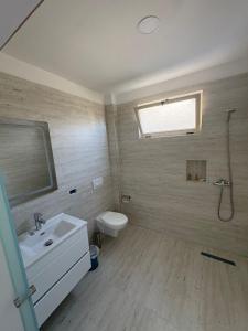 a bathroom with a sink and a toilet and a window at Hotel SKURA , Librazhd in Librazhd