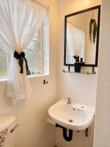 a white bathroom with a sink and a mirror at Zhantique Guest House 2- Unit 4 in Boksburg
