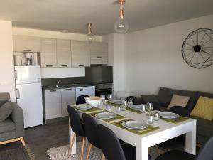 a living room with a white table and a kitchen at Porto-Vecchio 2-bedroom apartment, pool in Porto-Vecchio +10 photos