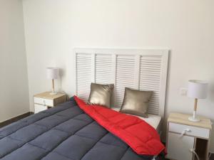 a bedroom with a large bed with a red blanket at Porto-Vecchio 2-bedroom apartment, pool in Porto-Vecchio