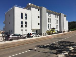 a white building with cars parked in front of it at Porto-Vecchio 2-bedroom apartment, pool in Porto-Vecchio