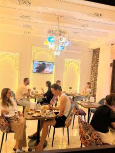 a group of people sitting at tables in a restaurant at GUZAL Boutique Hotel in Bukhara
