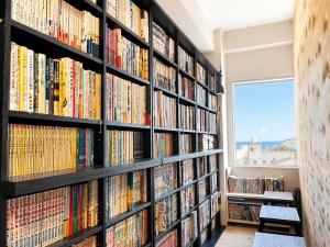 a book shelf filled with books in a library at ArtBar & GuestHouse ennova in Atami