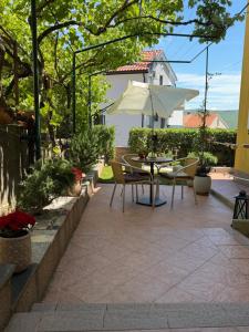 a patio with a table and chairs and an umbrella at Apartmani Grguric in Kornić