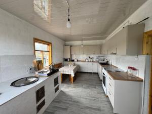 a large kitchen with white cabinets and a table at Guesthouse Snow Leopard - 'Ak Ilbirs' in Tong