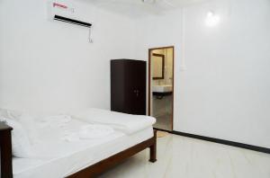 a white bedroom with a bed and a mirror at Villa Vianna in Nilaveli