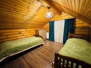 a bedroom with two beds in a log cabin at Уютный Деревянный дом в Кикети in Kiketʼi