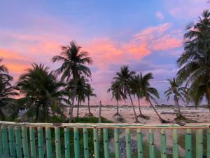 a view of a beach with palm trees and a fence at Kapunoan Beach House in Burgos