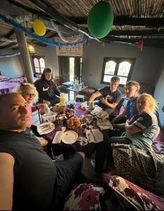 a group of people sitting around a table eating at Maison Riad Tamarighte in Merzouga +70 photos