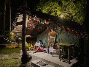 a person sitting in front of a tent with a laptop at Delft Village Stay - Experience Based Local Island Stay in Jaffna in Delft East