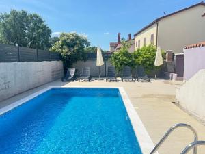 a swimming pool in a yard with chairs and umbrellas at Flora relax house, free parking in Peroj