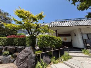 a house with a tree and rocks in front of it at 勝山恐竜博物館まで車で10分最大10名様ふとん屋の宿 悦 in Katsuyama