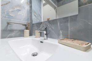 a bathroom with a white sink and a faucet at Flow Urban Living by DiffeRent in Ferrara +30 photos