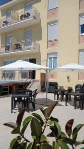 a patio with tables and umbrellas in front of a building at Piccolo Hotel in Lavagna