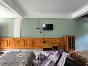 a bedroom with two beds and a tv on the wall at Zen Homestay in Dirang Dzong