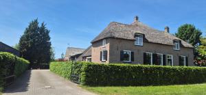 a brick house with a hedge in front of it at Betuwe Huisje in Meteren