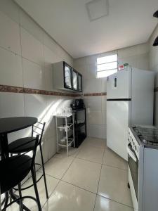 a small kitchen with a white refrigerator and a table at House farol in Aracaju