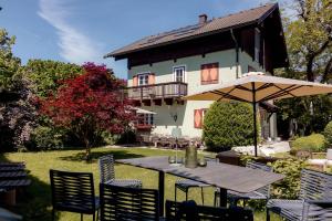 a table with an umbrella in front of a house at Villa Stella all famous ski areas around us, 15 minutes to salzburg, mountainview in Golling an der Salzach