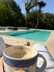 a person holding a coffee cup with live simply written on it at Coin de Paix - Château de Launay in Saint-Vincent-sur-Oust