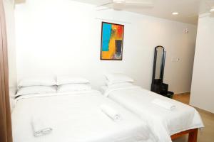 two beds in a room with white sheets at Shri Valli Rooms in Tiruvannāmalai