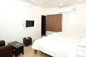 a bedroom with a bed and a tv on the wall at Shri Valli Rooms in Tiruvannāmalai