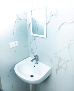 a white bathroom with a sink and a mirror at Shri Valli Rooms in Tiruvannāmalai +13 photos