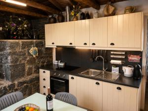 a kitchen with white cabinets and a sink and a table at Casinha de Pedra in Cais do Pico +10 photos