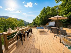 a wooden deck with chairs and tables and an umbrella at Charming family Chalet for 8 people, with private Hot Tub in Les Clefs +30 photos