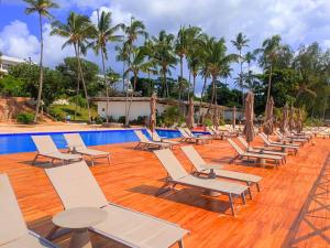 a row of lounge chairs and a pool with palm trees at Royal Mandarin Hotel & Resort Zanzibar in Pwani Mchangani
