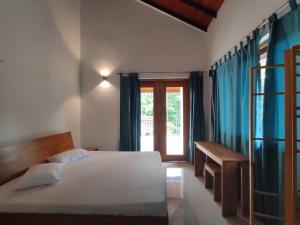 a bedroom with a bed and a desk and a window at Parrot Paradise Negombo in Negombo