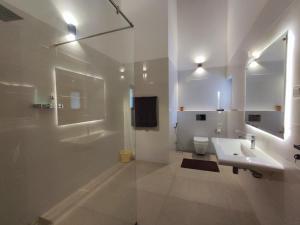 a white bathroom with a sink and a toilet at Parrot Paradise Negombo in Negombo