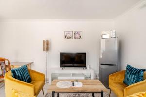 a living room with two chairs and a refrigerator at Sintha Guesthouse in Kraaifontein