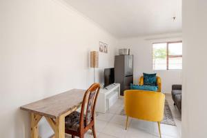 a dining room with a table and yellow chairs at Sintha Guesthouse in Kraaifontein