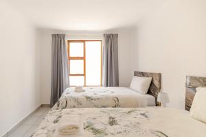 two beds in a room with a window at Sintha Guesthouse in Kraaifontein