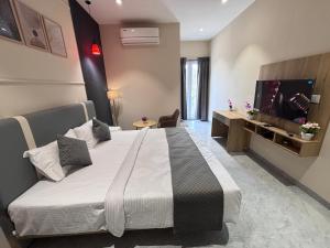 a bedroom with a large bed and a flat screen tv at Hotel Stayvilla Raipur in Raipur