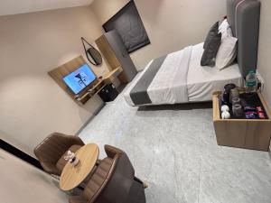 a bedroom with a bed and a chair and a tv at Hotel Stayvilla Raipur in Raipur