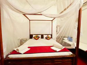 a bedroom with a canopy bed with a red blanket at Golden Breeze Arugambay in Arugam Bay