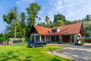 a house with a car parked in the yard at K Manor in Vāzhākulam