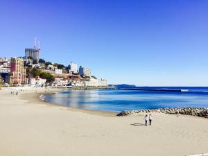 two people standing on a beach near the ocean at ArtBar & GuestHouse ennova in Atami